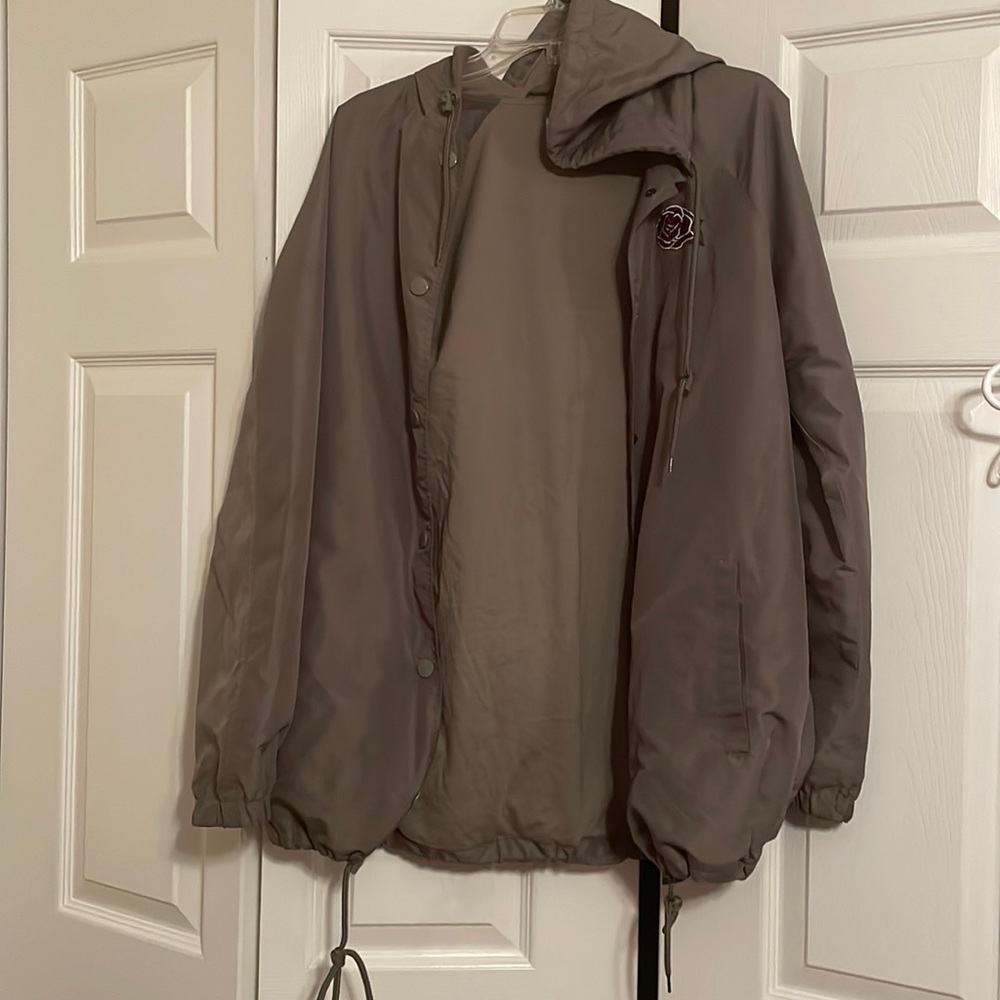 Olive green light weight jacket with a rose near the right shoulder